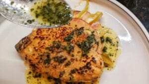 spooning pork mojo sauce onto pan fried cuban stuffed pork chops recipe