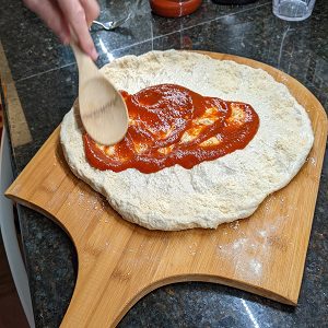 spreading sauce for a pepperoni pizza homemade