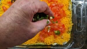 sprinkling layer 6 of diced green onions across top of 7 layer dip recipe