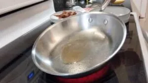 swirling oil around in stainless steel pan for cooking scrambled eggs recipe