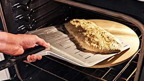 transferring calzone using metal pizza peel to pizza stone in oven transferring calzone using metal pizza peel to pizza stone in oven