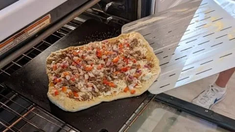 transferring prepared pizza to oven preheated pizza steel