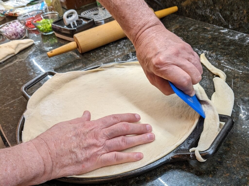 Trim off excess dough from cast iron pizzas surface